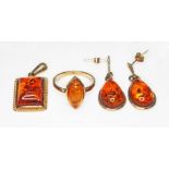 A suite of 9ct gold amber jewellery comprising a ring, a pendant and a pair of drop earrings, the