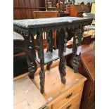 An eastern ebonised and carved wood occasional table.