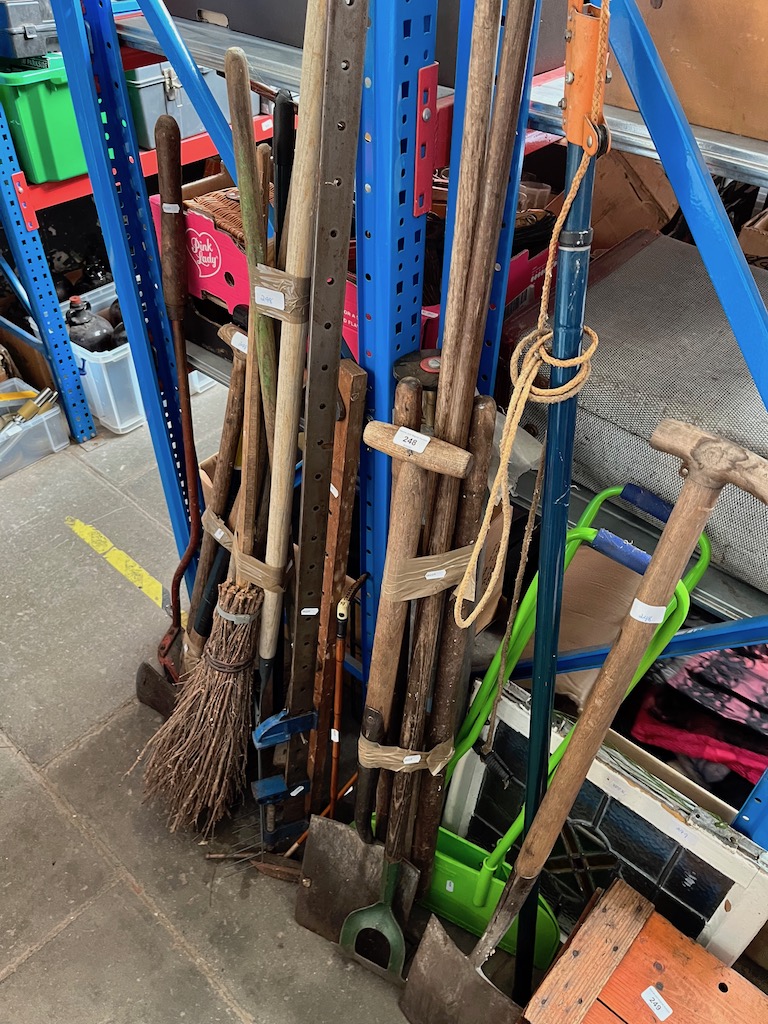 A collection of garden tools and drain rods and brushes