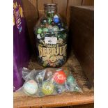 A Greenall's beer jug containing glass marbles, and a bag of bollies