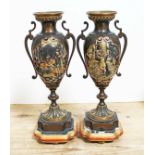 A pair of mixed metal urns decorated with scenes from Shakesspeare, on polychrome bases, height 29.