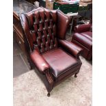 A brown leather Chesterfield wingback armchair.