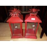 A pair of red painted candle lanterns.