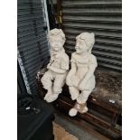 Two concrete garden figures in sitting position.