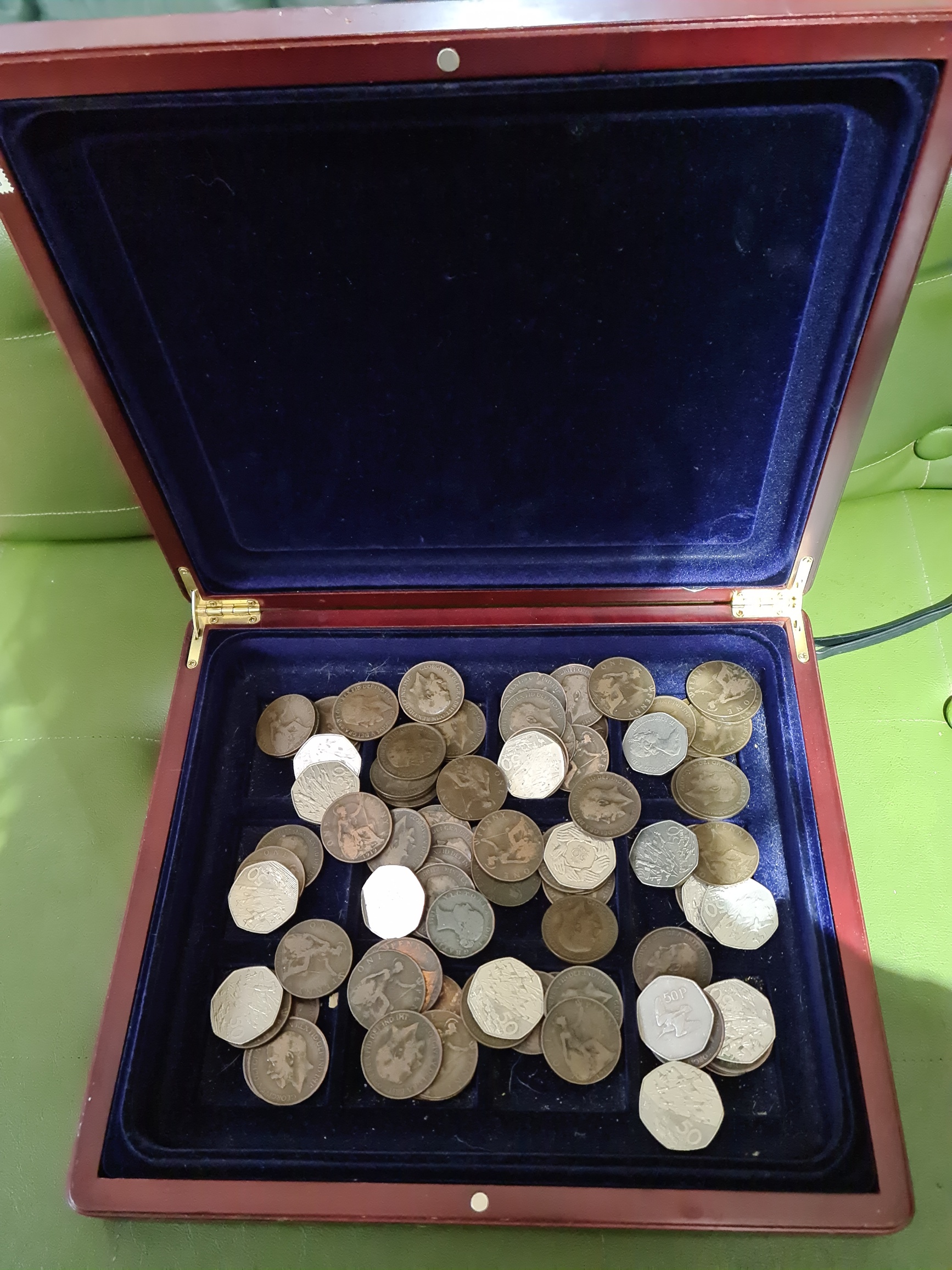 A wooden box of old pennys and 50p's