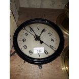 A vintage black painted metal circular clock with integrated pendulum, marked "British Make".