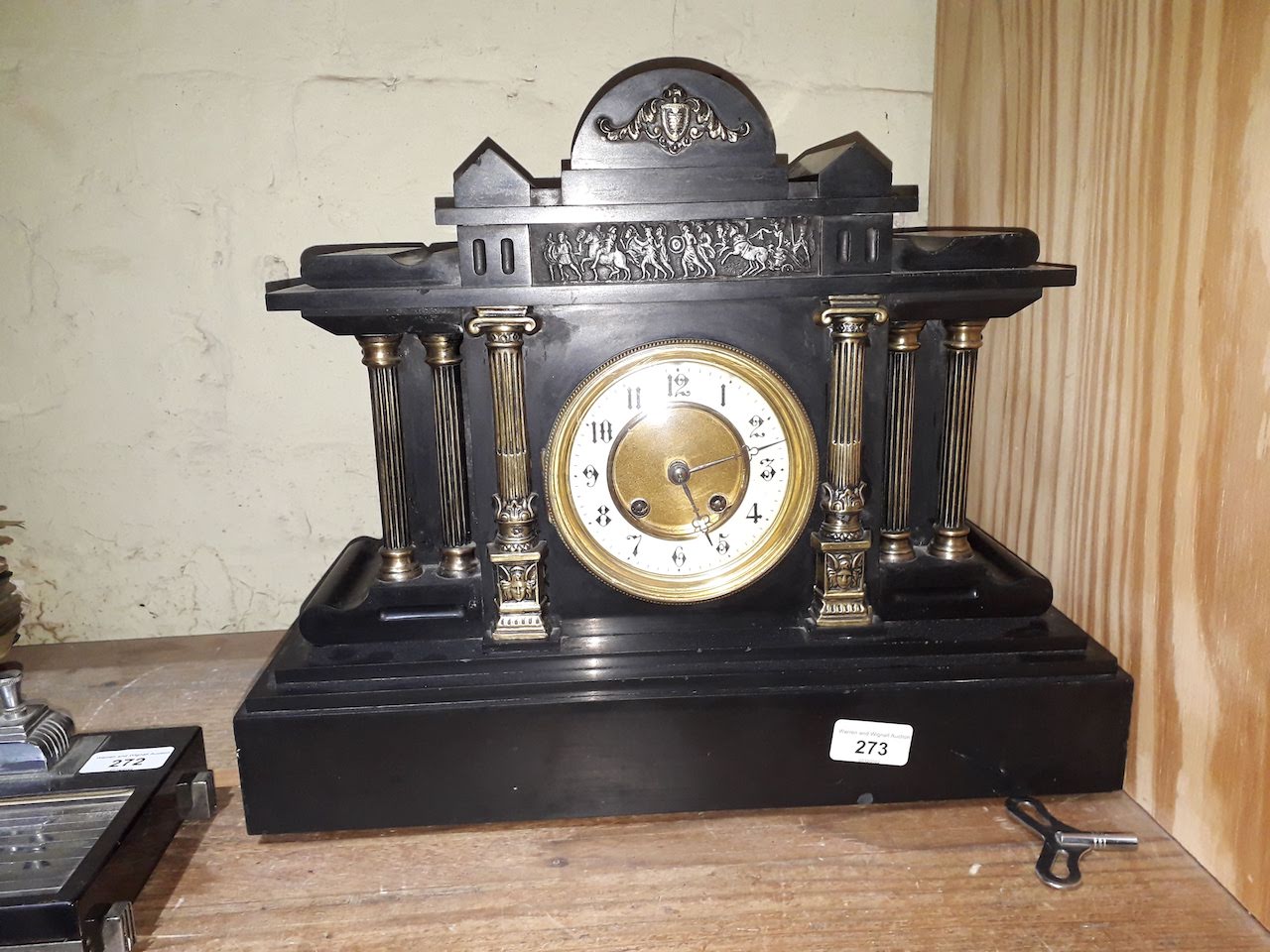 A black slate mantel clock with brass and enamel face, key and pendulum.