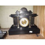 A black slate mantel clock with brass and enamel face, key and pendulum.