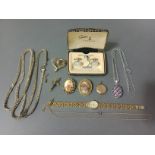 A selection of costume jewellery to include a 9ct gold back and front locket, chains, brooches, a