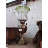 A brass oil lamp with funnel and etched green glass shade.
