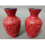 A pair of Chinese red cinnabar vases, with blue enamel interior and base, carvings depicting