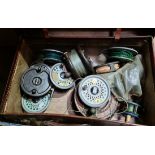 A box of assorted mainly fly reels and spoons.