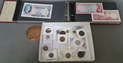 A tray of world coins & tokens to include some hammerd and a folder of world bank notes.