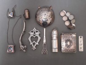 A collection of silver and white metal items including small notes book, tea strainer, ingot