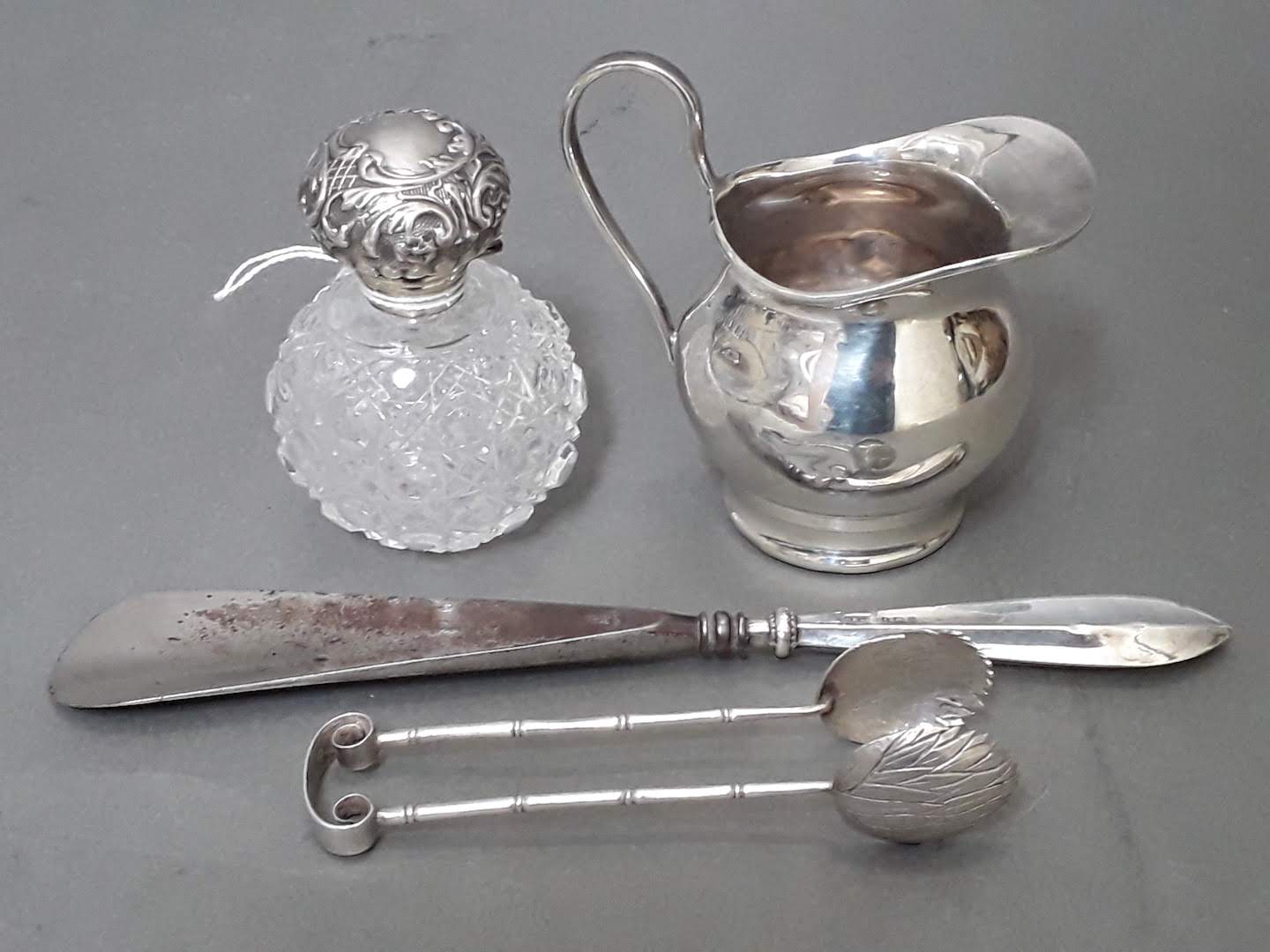 Assorted hallmarked silver comprising a milk jug, a pair of sugar tongs, a silver handled shoe