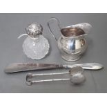 Assorted hallmarked silver comprising a milk jug, a pair of sugar tongs, a silver handled shoe