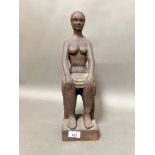 A carved wooden figure of a lady sat down