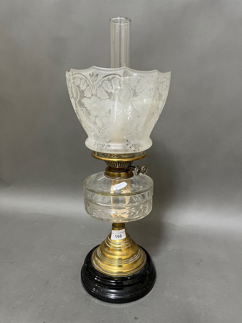 A brass oil lamp with cut glass reservoir and etched glass shade.