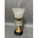 A brass oil lamp with cut glass reservoir and etched glass shade.