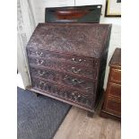 A Georgian oak bureau with later Victorian carved details.