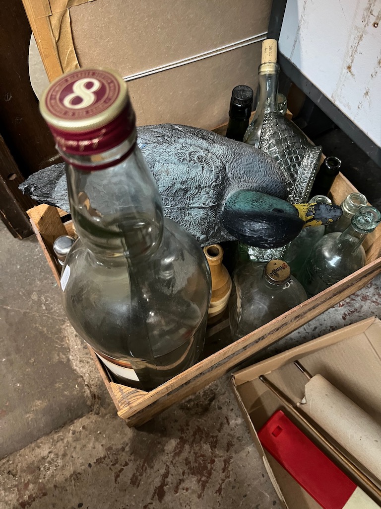 A box of bottles including an empty gallon Bells whisky bottle