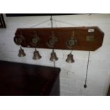 A set of four servant's brass bells mounted on later oak plaque, length 81cm.