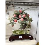 An artificial bonsai style fruit tree bearing plums, on oriental style wooden base