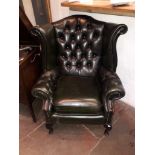 A green leather Chesterfield wingback armchair.