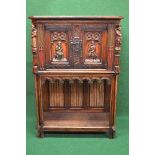 Oak carved side cabinet having cut corners the top having two panelled doors decorated with carved