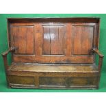 Period oak settle having three panelled back supported by open arms leading to lift seat opening