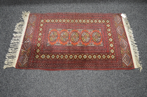 Red ground rug having yellow, rust and blue pattern with end tassels - 1.43m x 0.80m Please note