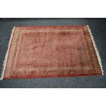 Red ground rug having blue and peach pattern with end tassels - 1.92m x 1.24m Please note