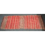 Red ground rug having white and black striped pattern with end tassels - 2.40m x 0.96m Please note
