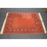 Late 20th century terracotta ground rug with grey and cream pattern and end tassels - 1.97m x 1.