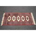Red ground rug with cream and black pattern and end tassels - 1.45m x 0.64m Please note descriptions