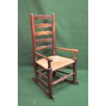 Oak ladderback rocking elbow chair having rush seat on turned stretchered legs Please note