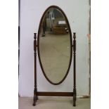 Mahogany Framed Oval Cheval Mirror with bevelled edge, the top of the frames holding two brass