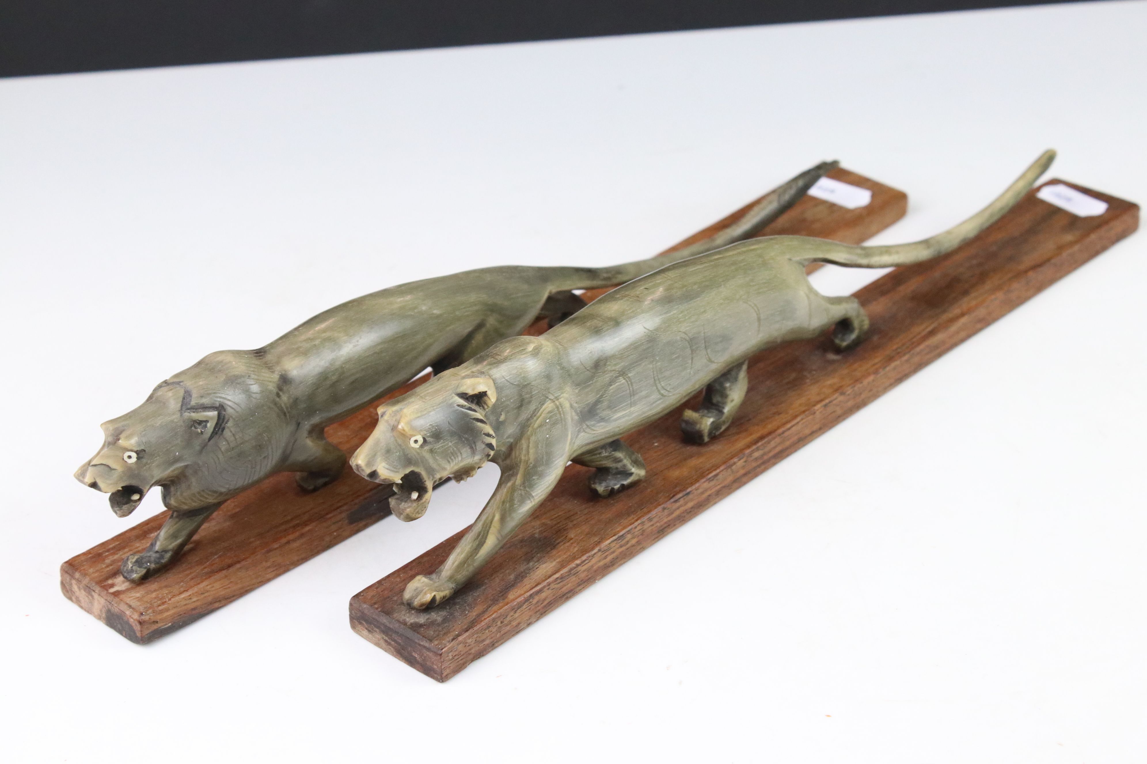 A pair of Art Deco carved horn tigers mounted to wooden bases.