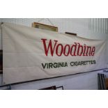 A large canvas "Woodbine Virginia Cigarettes" advertising banner.