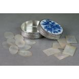 A collection of antique Chinese mother of pearl gaming tokens contained within a white metal box.