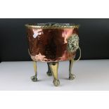 Copper Circular Planter with two brass ringed lion mask handles and raised on four tall brass lion