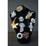 A collection of twelve vintage brooches on a display neck.