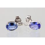 Pair of tanzanite and diamond 18ct white gold earrings, the oval mixed cut tanzanite measuring