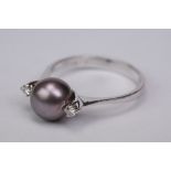 Black pearl and diamond 18ct white gold ring, the central cultured black pearl with pink overtones,