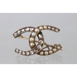 Victorian diamond and pearl unmarked yellow gold brooch modelled as two entwined horseshoes,