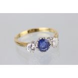 Sapphire and diamond three stone 18ct yellow gold ring, the central oval mixed cut blue sapphire