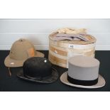 A collection of three hats to include a top hat, a bowler hat and a pith helmet.