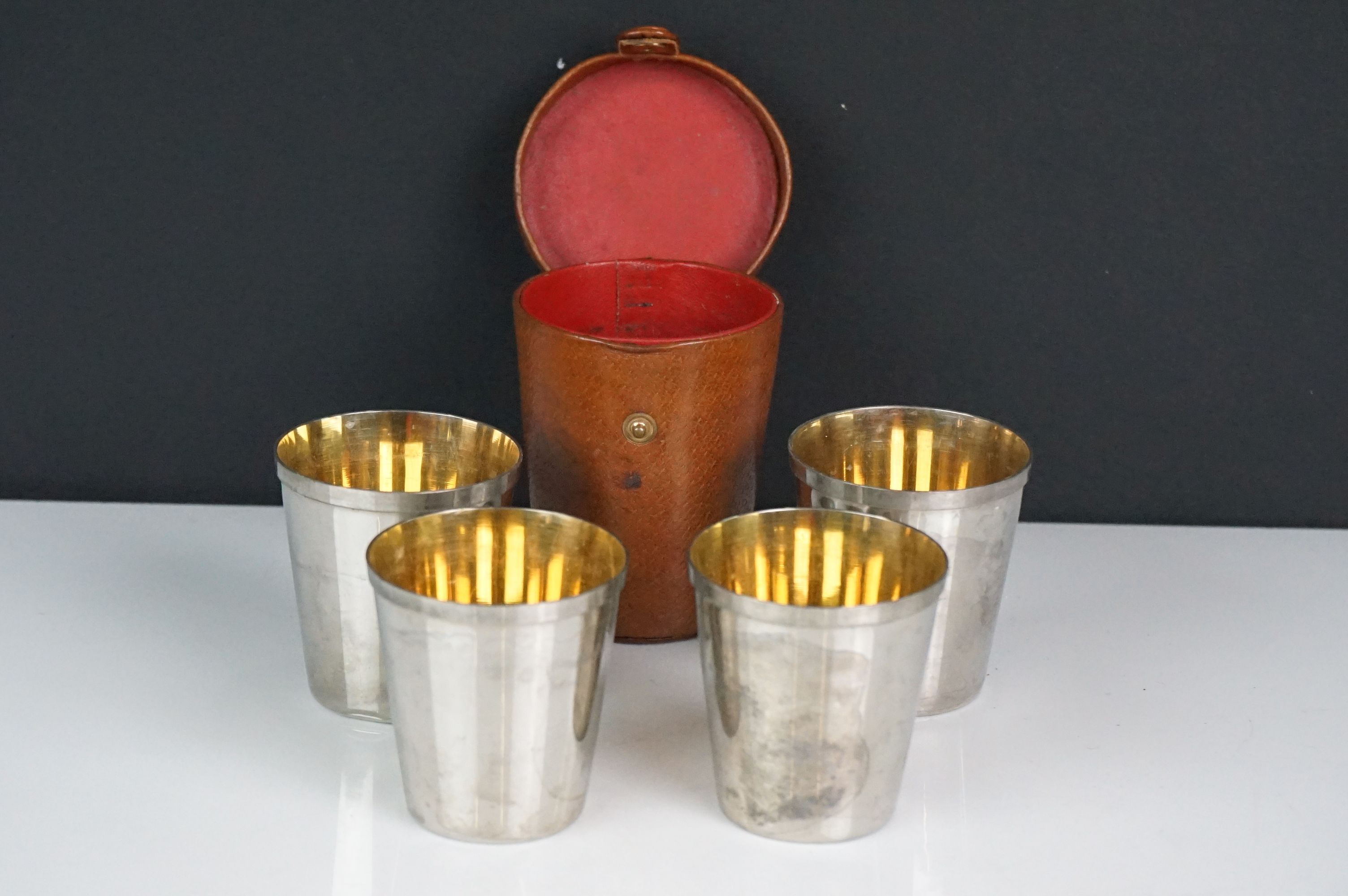 A set of four silver plated stirrup cups in brown leather case.