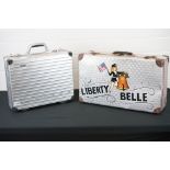 An aluminium case with Liberty Belle pin up girl decoration and a Rimowa aluminium case.