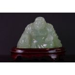 A carved jade figure in the form of a Buddha on fitted stand.